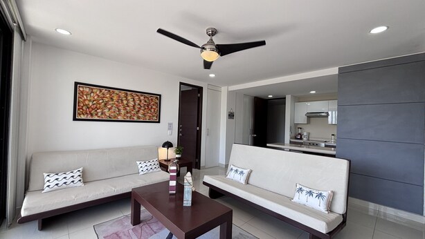 Uma sala de estar moderna com um sofá, uma mesa de centro e um ventilador de teto.