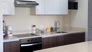 Uma cozinha moderna com armários brancos, uma coifa de aço inoxidável, micro-ondas e máquina de lavar louça.