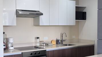 A modern kitchen with white cabinets, a stainless steel range hood, a microwave, and a dishwasher.