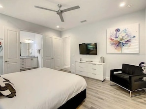 A modern bedroom with a bed, a TV, a ceiling fan, and a painting on the wall. - The Reserve at Reunion-TT492 (Kissimmee)