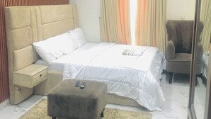 Um quarto com uma cama, mesa de cabeceira, cadeira, espelho e tapete.