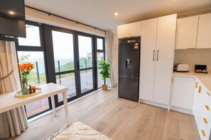 A modern kitchen with a built-in refrigerator, a dining table with a vase of flowers, and a view through the sliding glass doors.