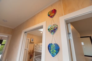 A room with a door leading to a hallway, a hanging heart-shaped decoration, and a visible light switch on the wall.