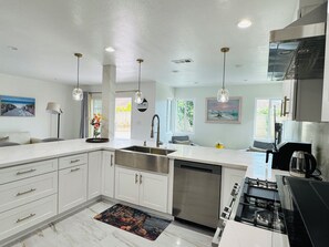 A modern kitchen with white cabinetry, a stainless steel sink, and a gas stove. - Cozy 2-bedroom unit in central Westminster, Orange County. (Westminster)