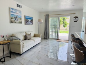 Ein modernes Wohnzimmer mit einer Couch, einem Couchtisch und einem Essbereich mit Stühlen.