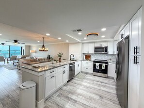 A modern kitchen with white cabinetry, a stainless steel refrigerator, and a built-in oven. - Punta Rassa 1-404: Water-view 2BR, 2BA condo in Punta Rassa, Fort Myers. (Fort Myers)