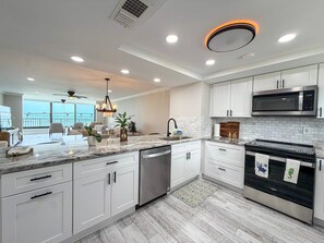 A modern kitchen with white cabinets, a stainless steel microwave, and a dishwasher. - Punta Rassa 1-404: Water-view 2BR, 2BA condo in Punta Rassa, Fort Myers. (Fort Myers)