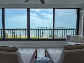 A room with a large window overlooking a bridge and water, two sofas, and a wooden floor. - Punta Rassa 1-404: Water-view 2BR, 2BA condo in Punta Rassa, Fort Myers. (Fort Myers)