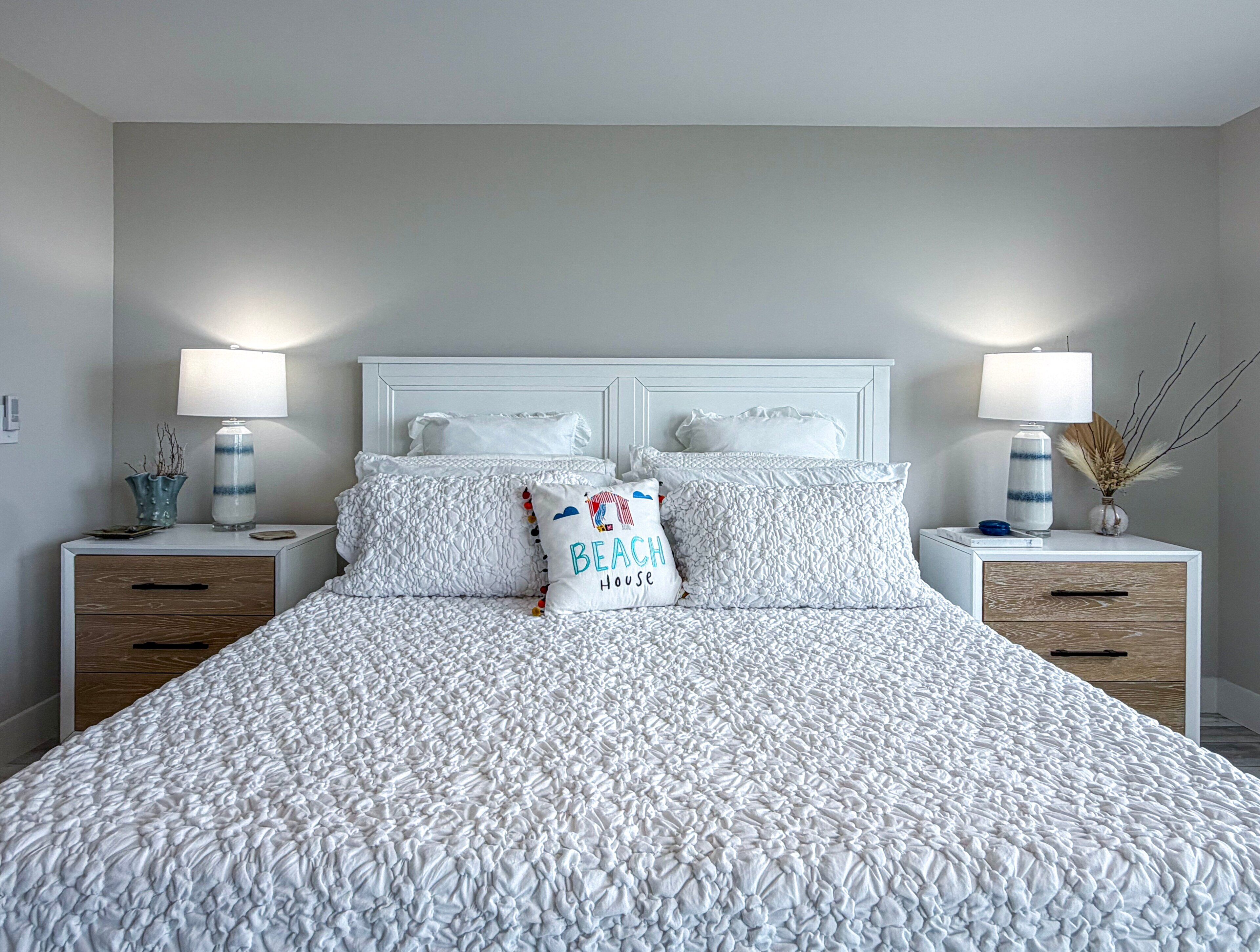 A bedroom with a large bed, two bedside tables, and a nightstand with a lamp.