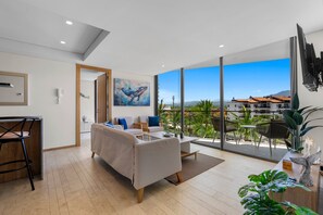 A modern living room with a sofa, a dining area, and a large window offering a view of a cityscape. - 1BR, 2BA condo in Marina Vallarta, Puerto Vallarta. (Puerto Vallarta)