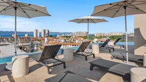 A rooftop pool area with lounge chairs and umbrellas, overlooking a marina and cityscape. - 1BR, 2BA condo in Marina Vallarta, Puerto Vallarta. (Puerto Vallarta)