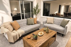 Un salon avec deux canapés gris, une table basse en bois et une plante en pot.