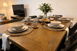 A dining table set with plates, bowls, and glasses, with a vase of flowers and a candle labeled 'THUNDER' on the table. - Casa Oliva | Spacious Retreat Near Toranga Zoo (Dubbo)