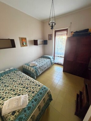 A room with two beds, a TV, a wardrobe, and a window with curtains. - VILLA MARELUCE (Santa Marinella)