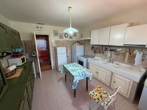 A compact kitchen with a dining table, a microwave, and a refrigerator. - VILLA MARELUCE (Santa Marinella)