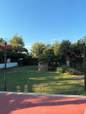 A well-maintained garden with a variety of plants and a stone planter in the center. - VILLA MARELUCE (Santa Marinella)