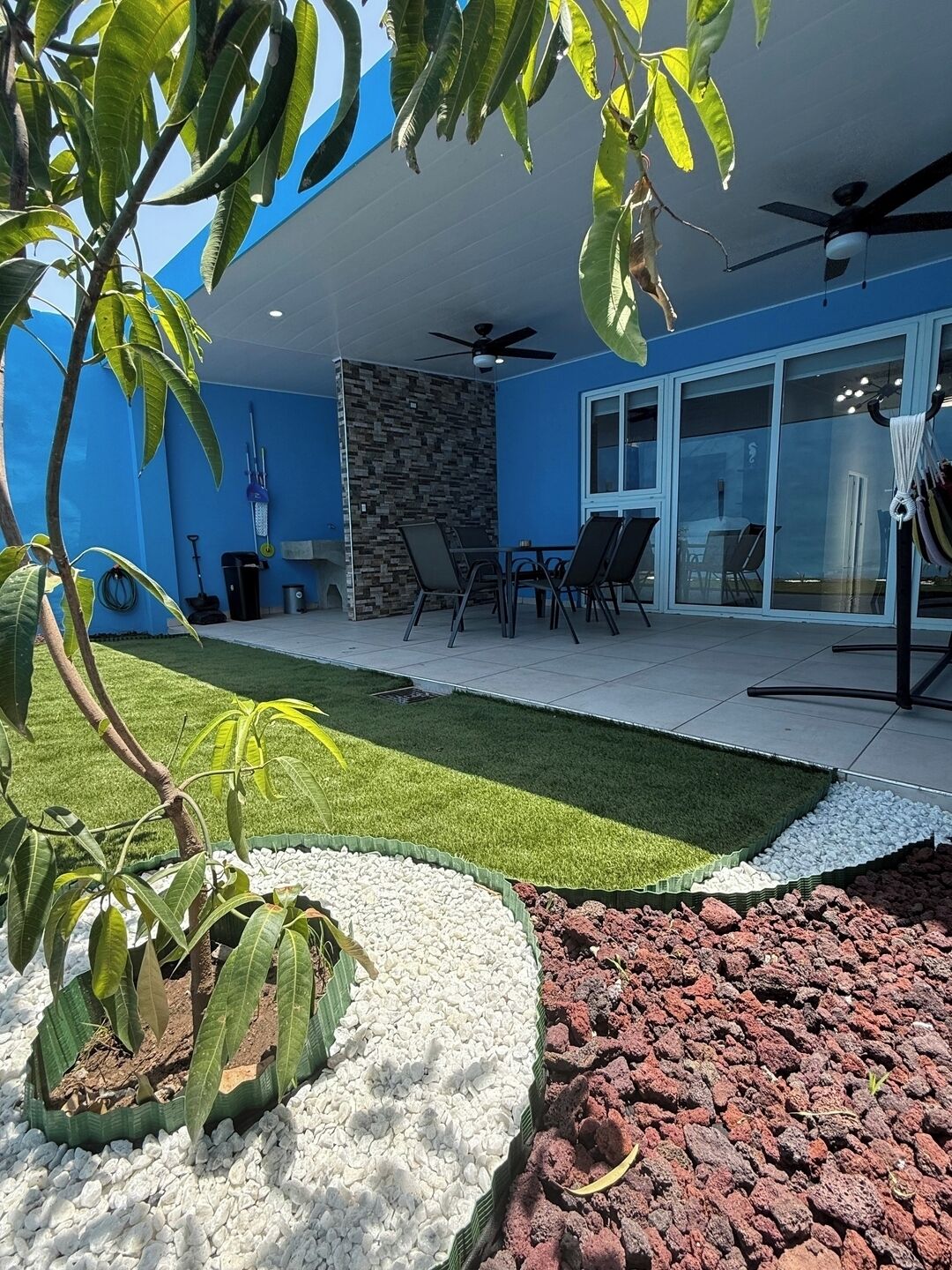 Een moderne patio buiten met gazon, zitgedeelte en een stenen muur.