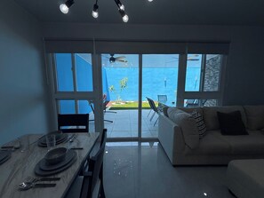 Ein modernes Wohnzimmer mit Essbereich, großen Fenstern und Meerblick.