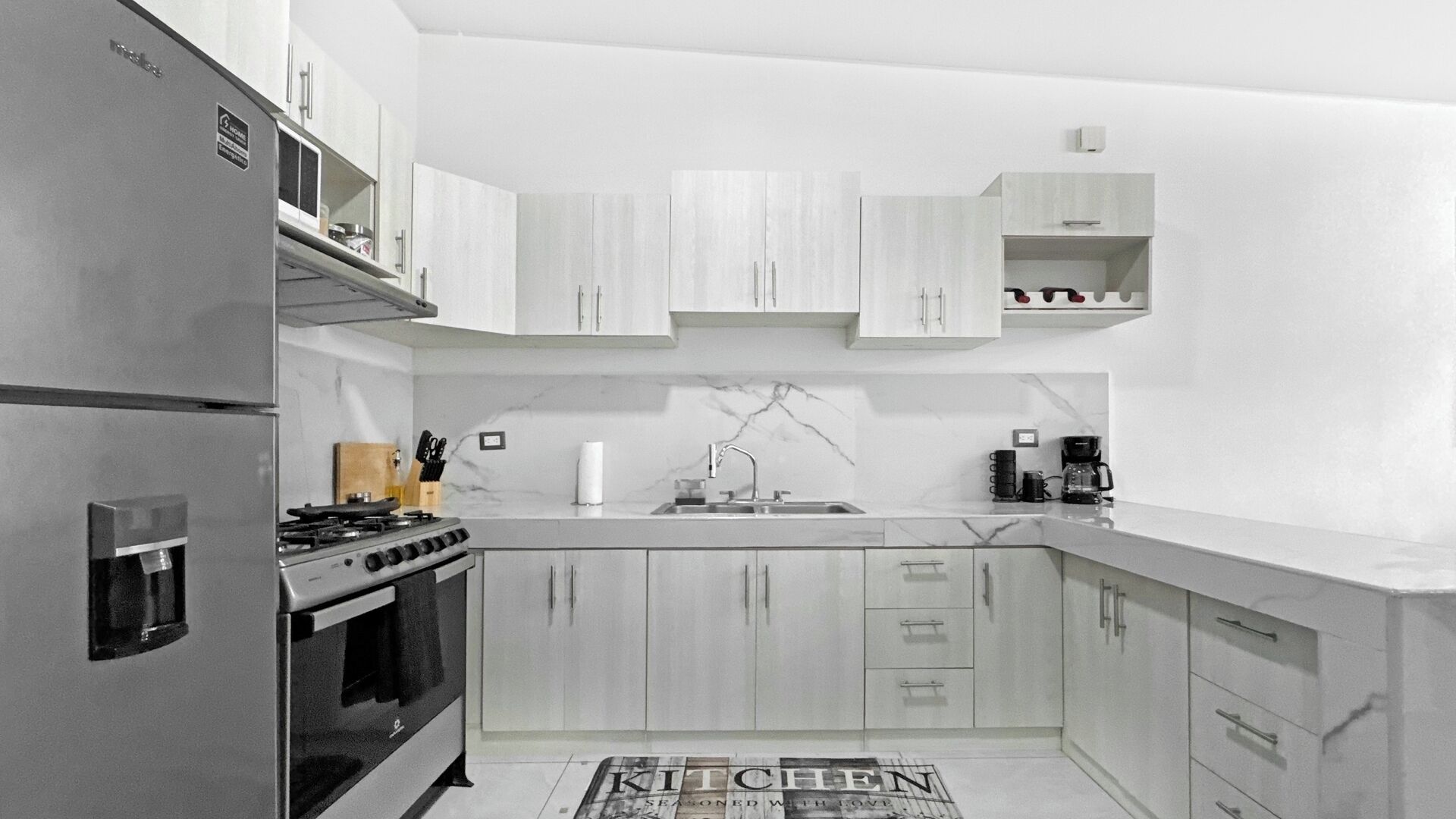 A modern kitchen with a built-in stove, stainless steel appliances, and light wood cabinetry.