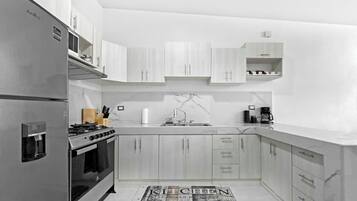 A modern kitchen with a built-in stove, stainless steel appliances, and light wood cabinetry.