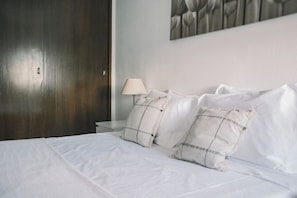 A neatly made bed with white bedding, two pillows, a bedside lamp, and a dark wooden door. - Quinta do Lambert Apartment by Trip2Portugal (Lisboa)