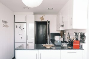 Eine moderne Küche mit weißen Schränken, einer schwarzen Arbeitsplatte und einer sichtbaren Tür zu einem anderen Raum.