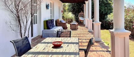 A covered patio with a table and chairs, a sofa, and a decorative chair.