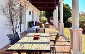 A covered patio with a table and chairs, a sofa, and a decorative chair.