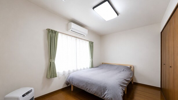 A bedroom with a bed, an air conditioner, a window with curtains, a ceiling light, and a wooden wardrobe. - Asahikawa Family Stay KT (Asahikawa)