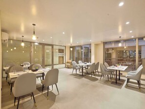 A modern dining area with glass partitions, recessed lighting, and contemporary furniture. - Palette Hotel Millennium City Gurugram (Gurugram)