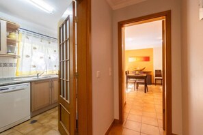 Eine Küche mit Geschirrspüler, Holzschränken und einem Fenster mit Vorhang.