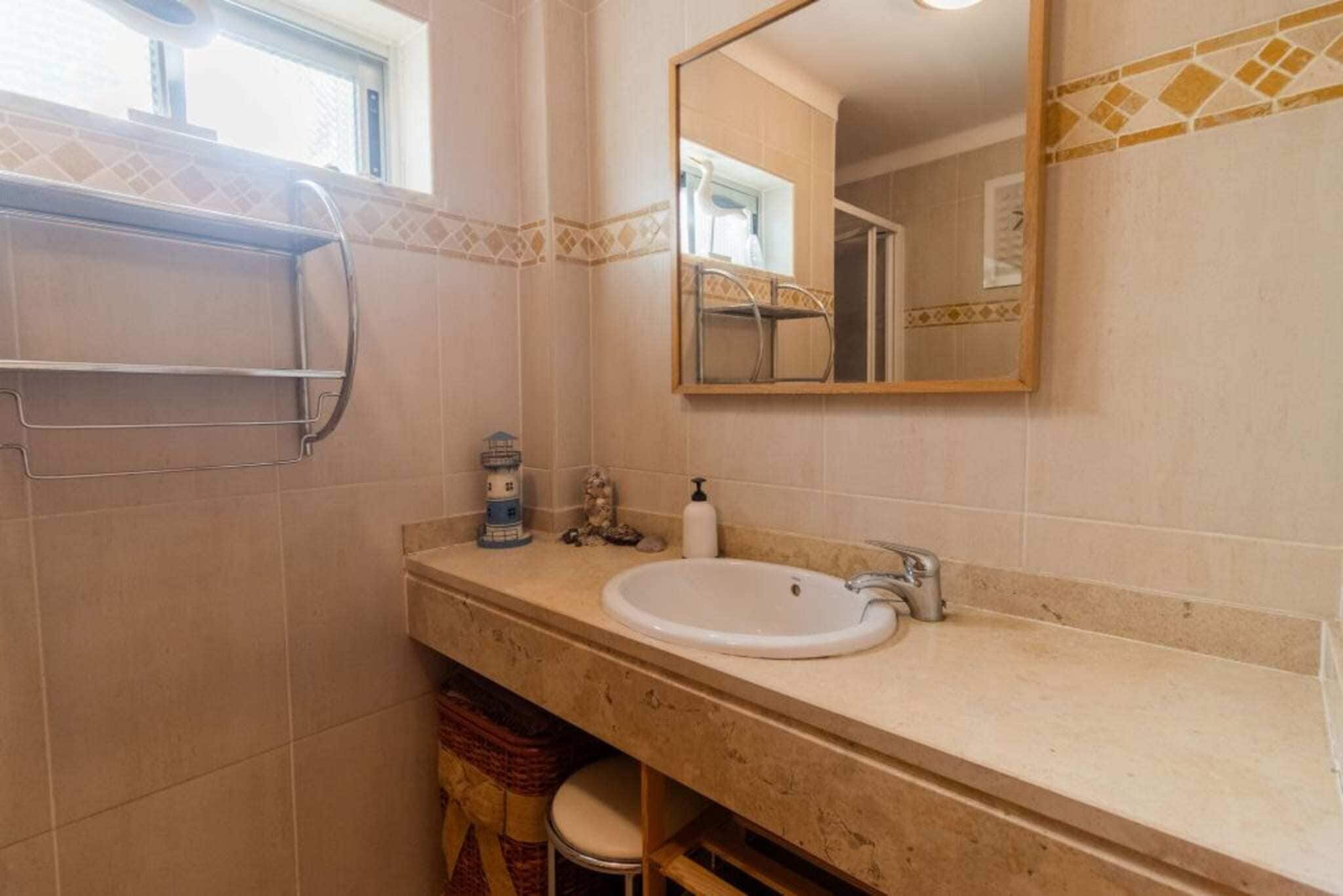 Un baño con lavamanos, espejo y toallero.