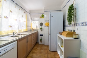 Eine Küche mit Geschirrspüler, Kühlschrank, Spüle und einer Pflanze an der Wand.