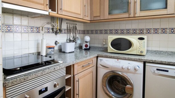 Cozinha equipada com micro-ondas, máquina de lavar, forno e utensílios diversos.
