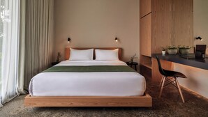 A modern hotel room with a wooden bed frame, a desk with a laptop, and a chair. - Nexa Townhouse 08 (Badung)