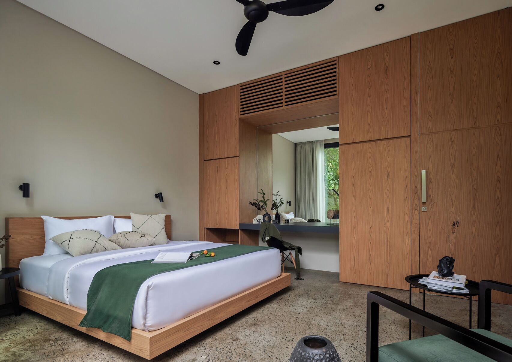 Un dormitorio moderno con cama, mesitas de noche, espejo y ventilador de techo.