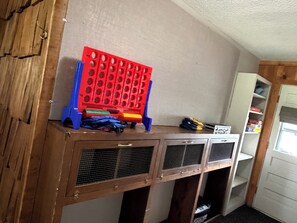 A room with a wooden cabinet, a red pegboard, and a white shelving unit.