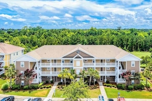 A multi-story hotel with a central courtyard, balconies, and a parking area. - Cozy 2-bedroom condo with AC in charming North Myrtle Beach (North Myrtle Beach)