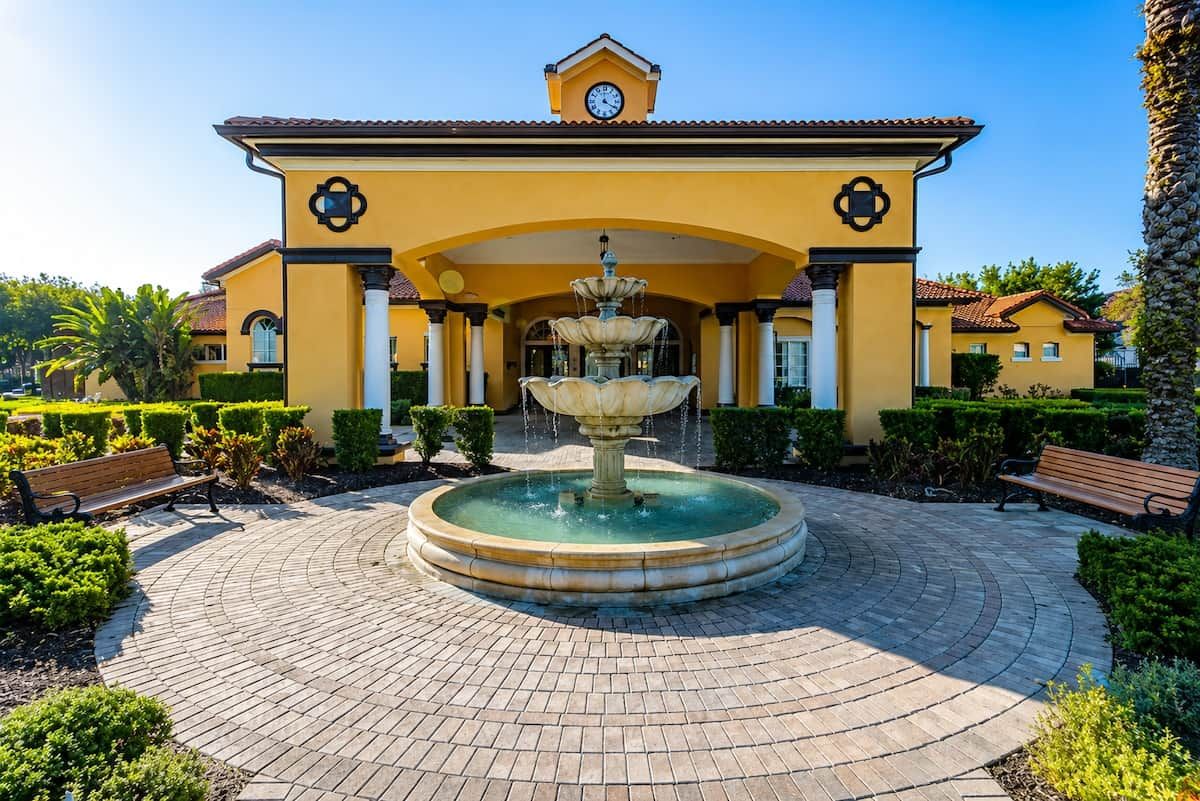 A building with a central fountain, surrounded by a paved courtyard with benches.