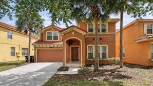 A residential building with a central entrance, multiple windows, and a driveway. - Luxury Getaway 4 Bd/5 Bath 25 Mins to DisneyMagic! (Davenport)