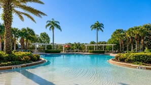 A clear swimming pool with a 6-inch depth marker, surrounded by palm trees and a pergola structure. - Luxury Getaway 4 Bd/5 Bath 25 Mins to DisneyMagic! (Davenport)