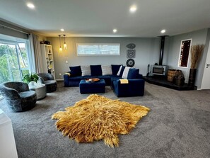 A modern living room with a sectional sofa, a round rug, and a fireplace. - Views @ Four Winds (Taupō)