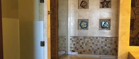Une salle de bain moderne avec une douche à l’italienne, une baignoire et des carreaux décoratifs.