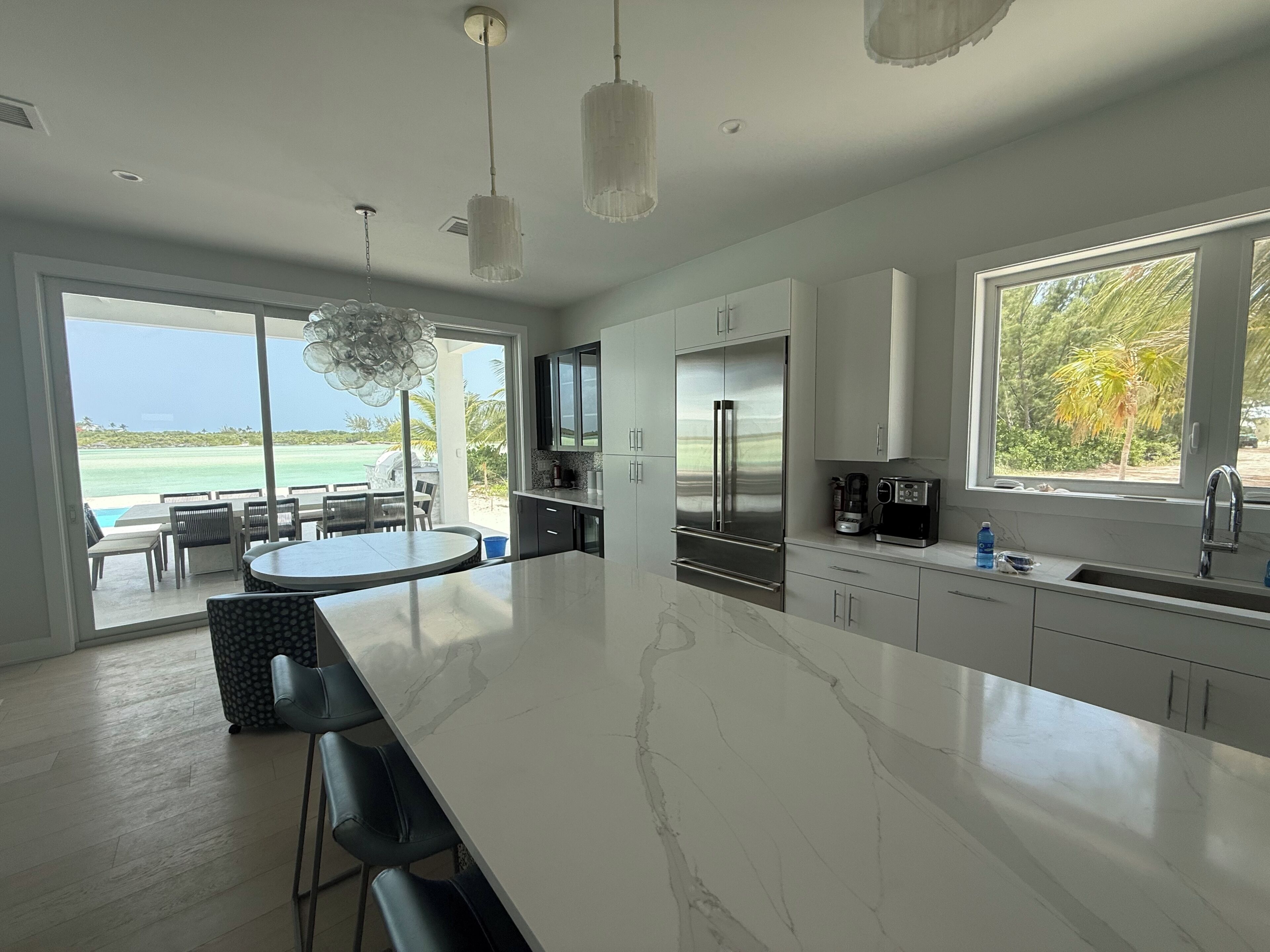 A modern kitchen with a large island, stainless steel appliances, and a view of the ocean.