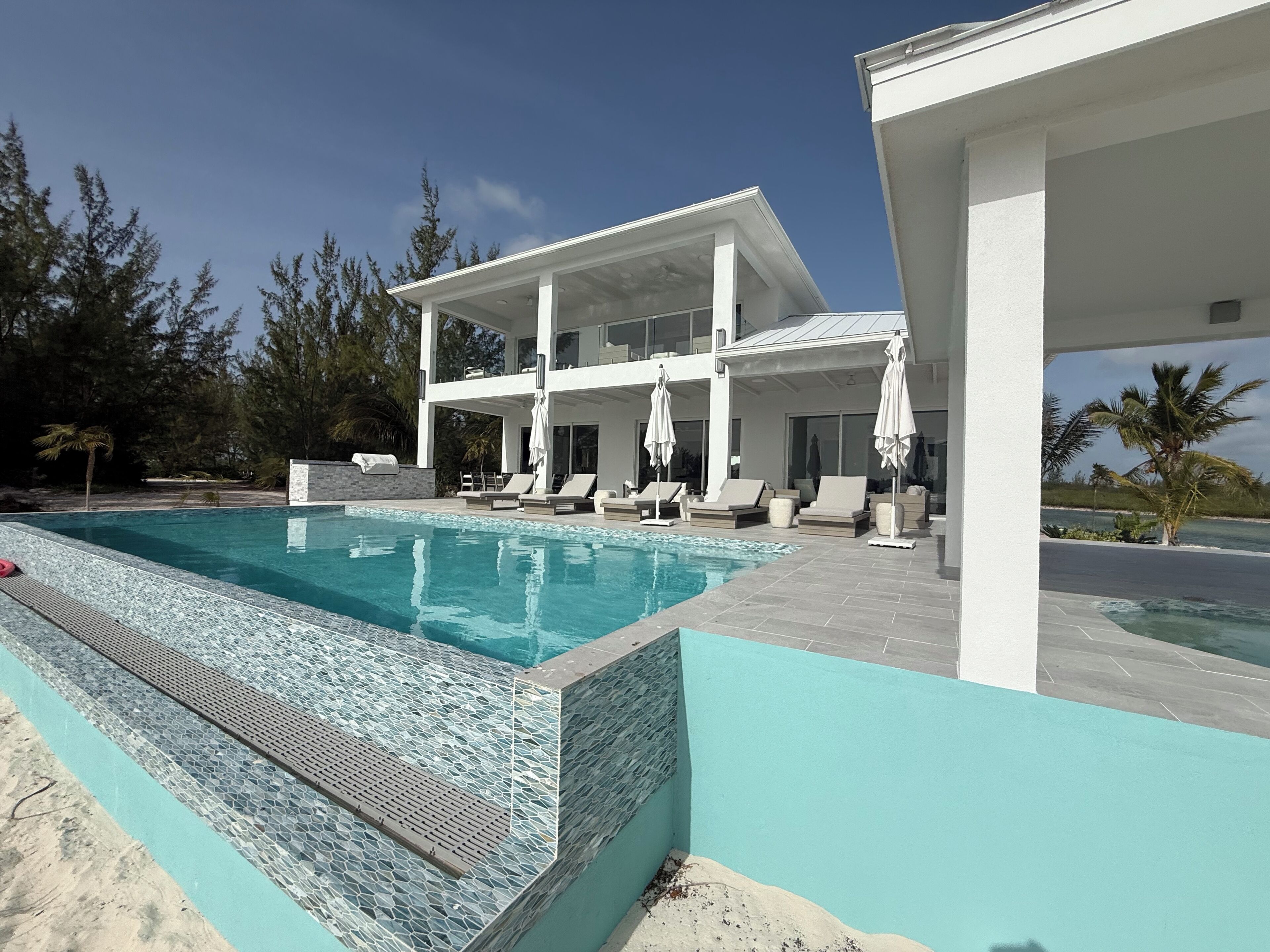 A modern pool with a tiled edge, lounge chairs, and umbrellas.