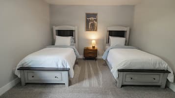A bedroom with two beds, a nightstand with a lamp, and a framed picture on the wall.