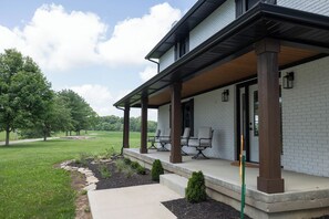 A house with a covered porch, a brick exterior, and a landscaped yard.