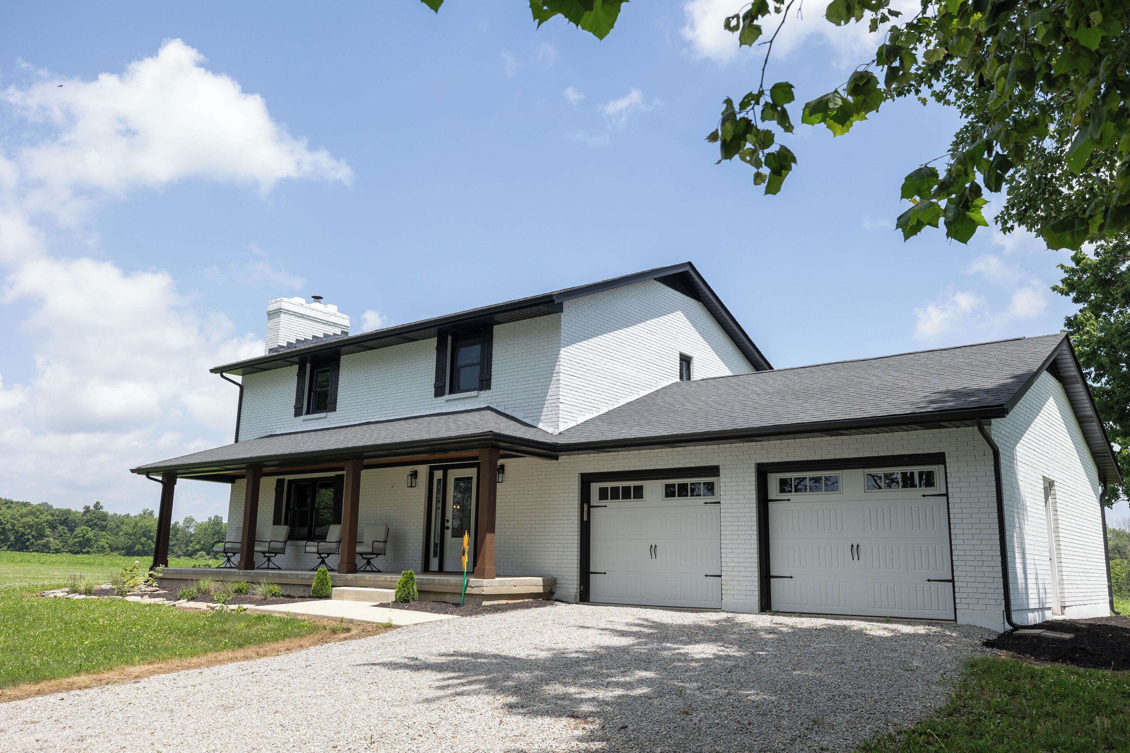 A two-story house with a covered porch, a garage, and a well-maintained lawn.