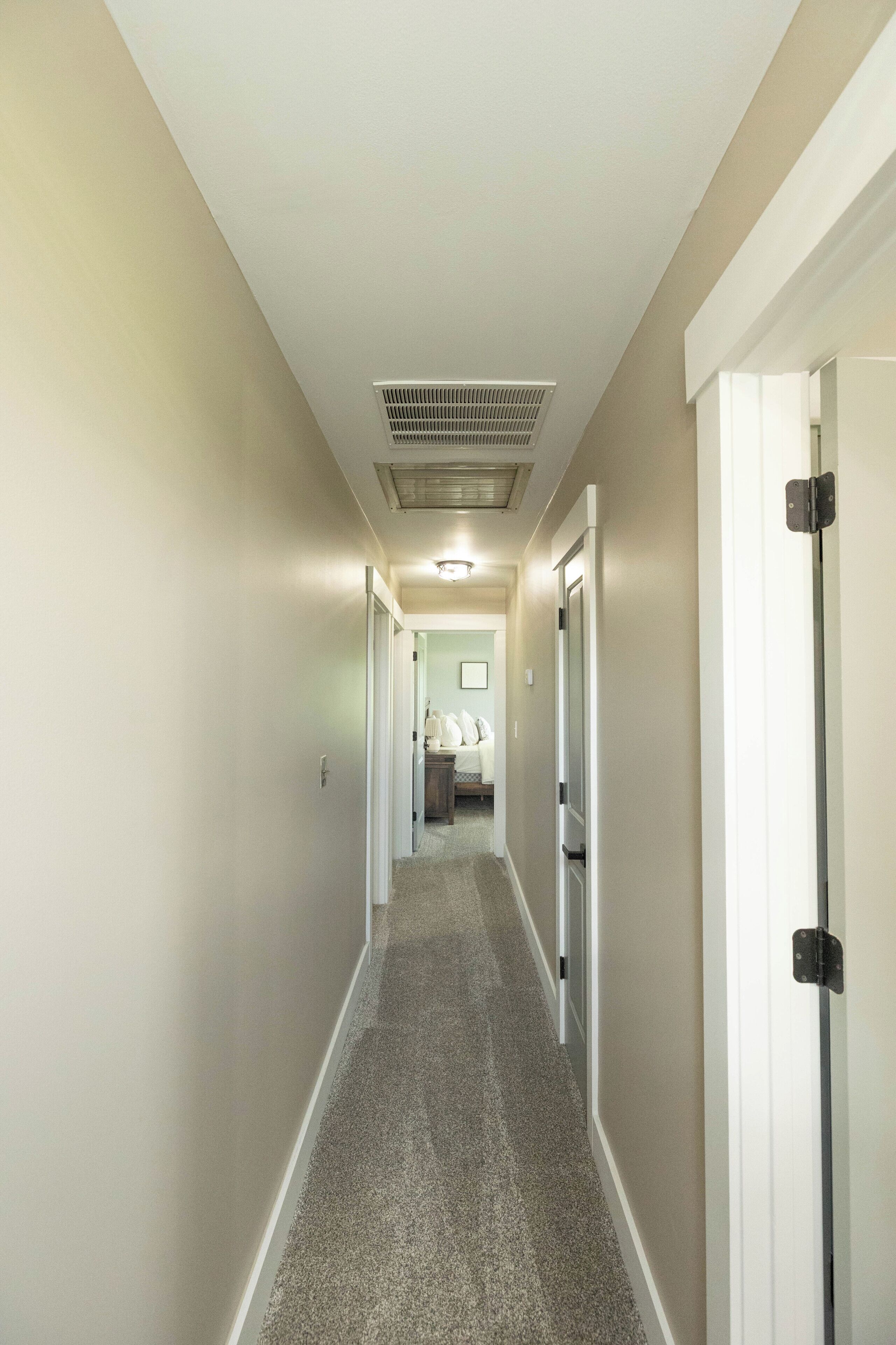 A hallway with carpeted flooring, white walls, and doors on both sides.