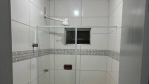 Ein Badezimmer mit Duschkabine aus Glas, Toilette und kleinem Fenster.